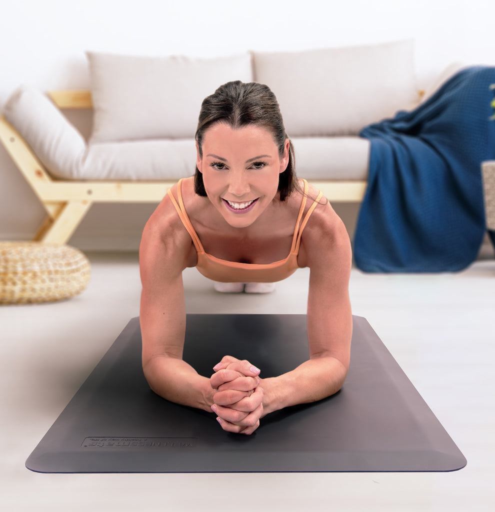 Woman doing plank on gray WellnessMat in living room