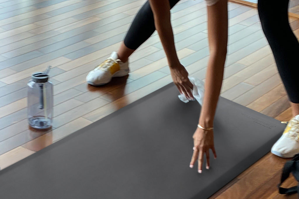 Woman wiping off a grey FitnessMat